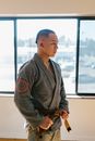 Man in Gray Kimono and Brown Belt Standing beside Glass Window