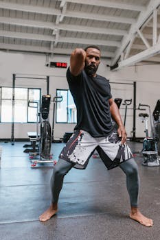 A man in sportswear demonstrating a karate pose indoors, showcasing strength and discipline.