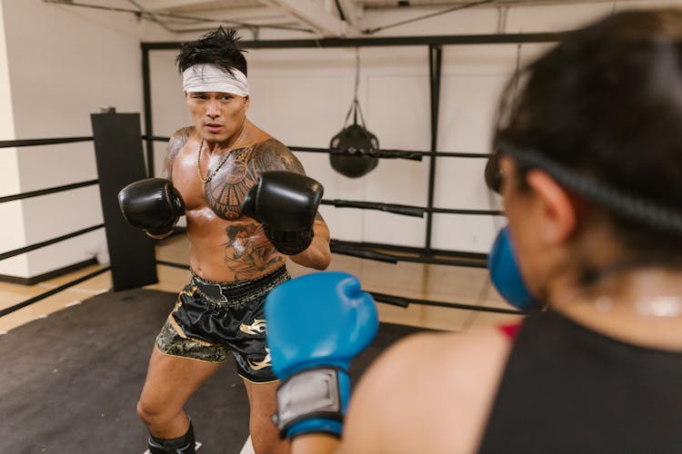 A Man In Black Shorts Wearing Boxing Gloves Sparring With A Woman