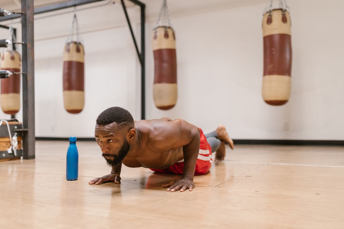 Focused person performing push-ups on a gym floor
