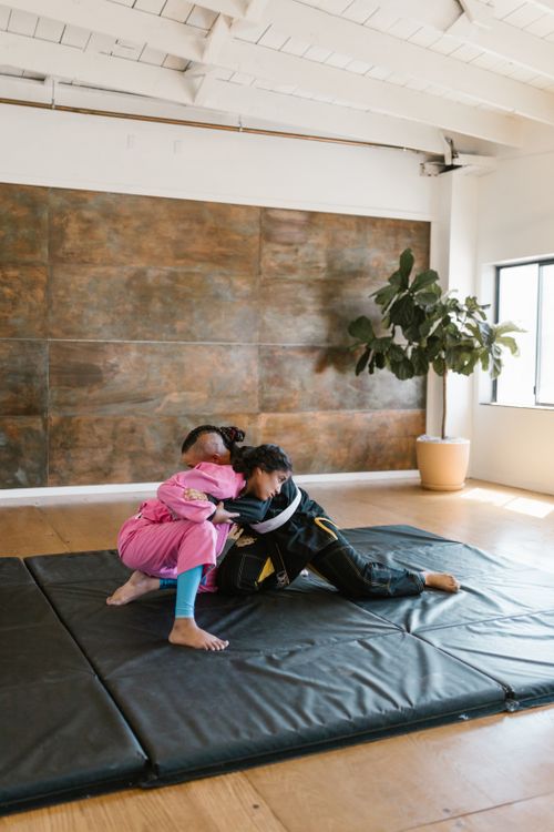 Free Two athletes spar in taekwondo uniforms on a mat inside a well-lit room. Stock Photo