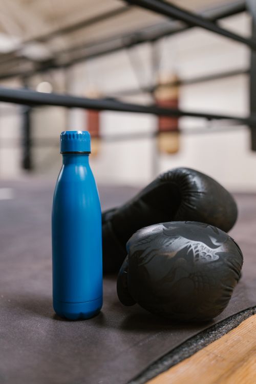 Free Close-up of a blue bottle and black boxing gloves on a gym ring floor Stock Photo