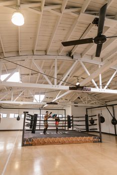Two boxers sparring in a spacious indoor ring during daytime training session.
