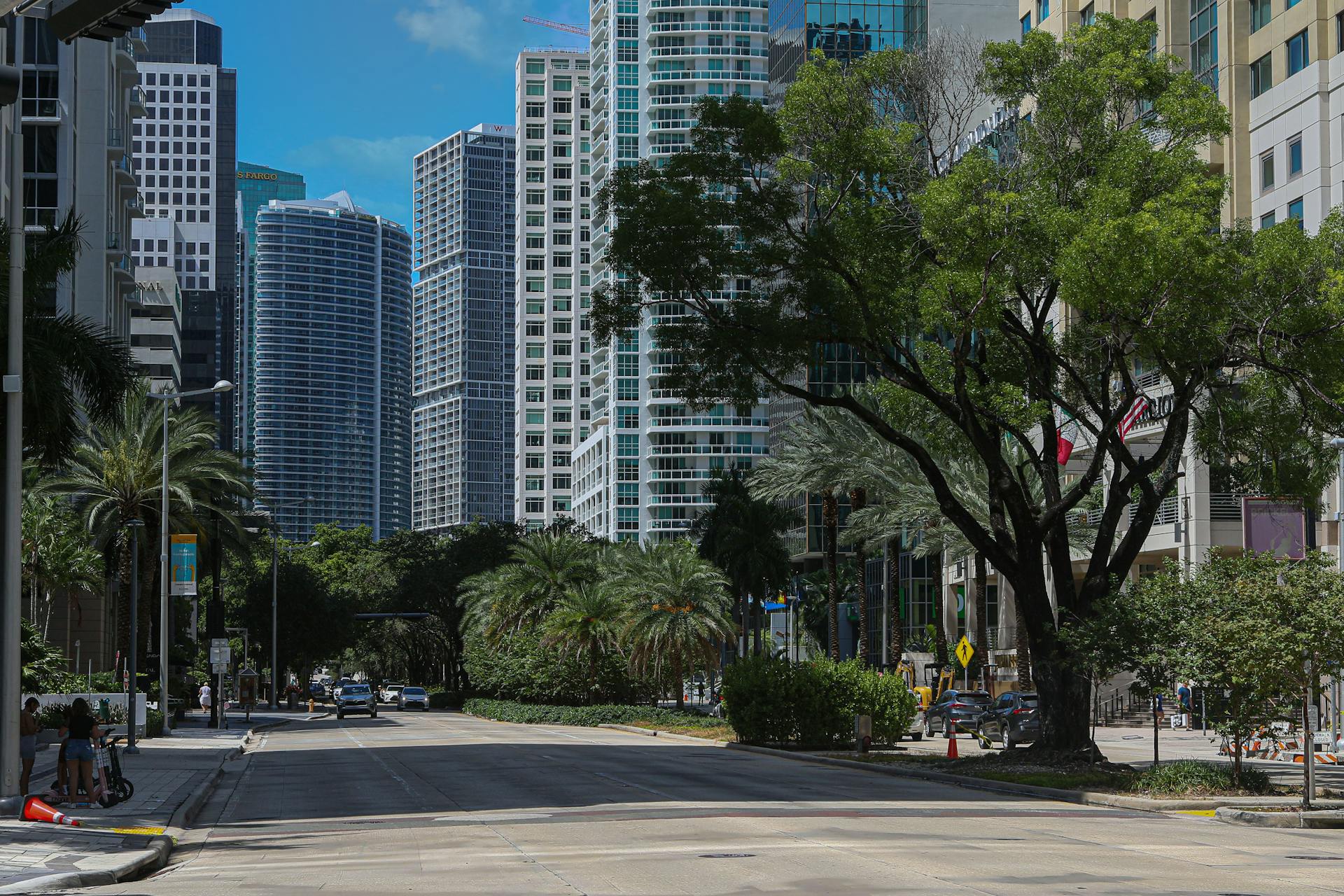 Lively street in downtown Miami featuring skyscrapers and lush palm trees under a bright blue sky.