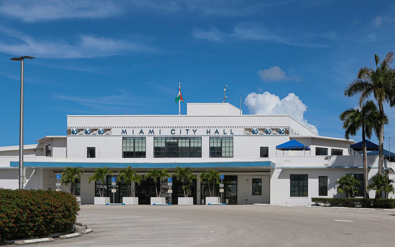 Front view of Miami City Hall with palm trees under a clear blue sky.