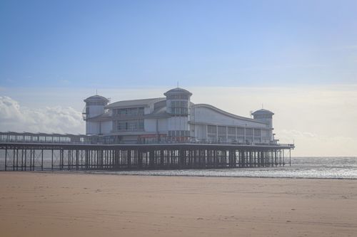 Free A picturesque pier stands against the ocean backdrop under a vibrant blue sky. Stock Photo
