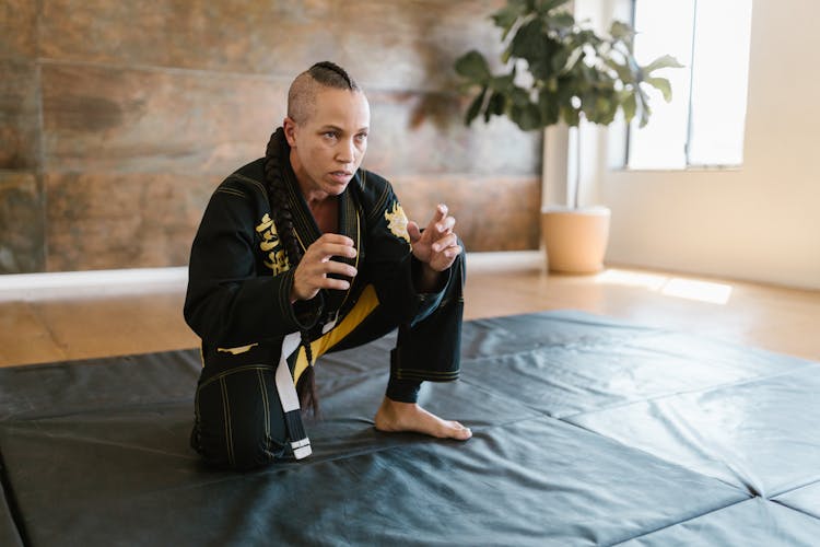 Woman In Black Karate Uniform On A Black Mat