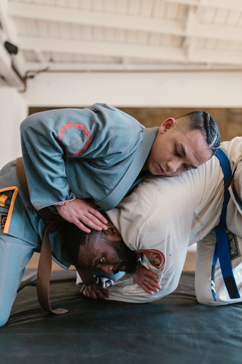 Two Men in Karate Uniform Wrestling on a Mat