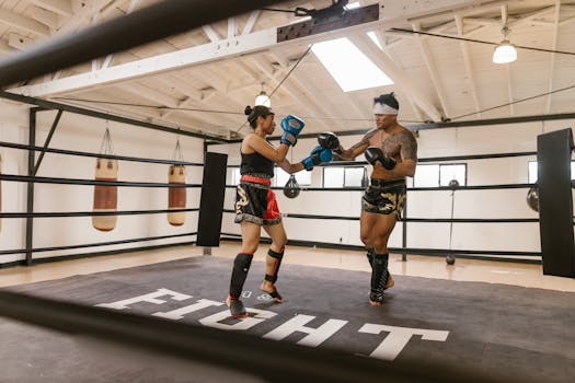 A man and woman training in a boxing gym, sparring in the ring with gloves.