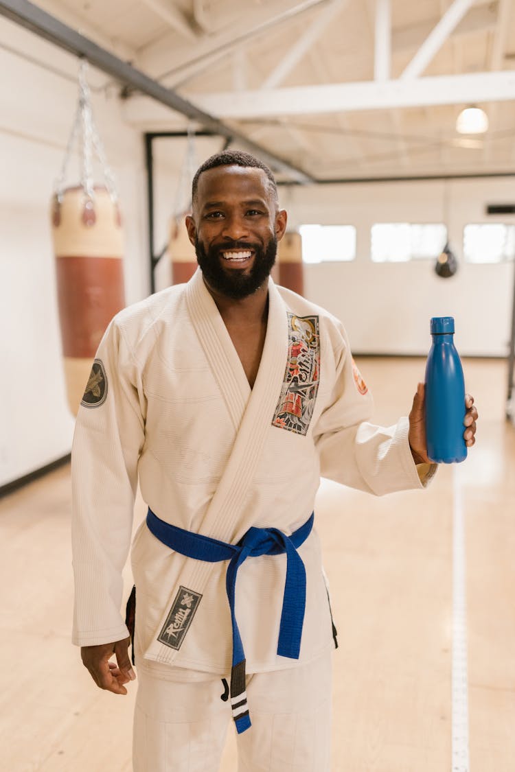 A Man Wearing White Gi Holding A Tumbler