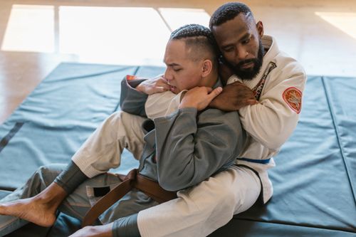 Free Two men practicing martial arts techniques in a gym setting, focusing on grappling skills. Stock Photo