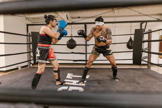 A man and woman engaged in a boxing sparring session in a training ring, showcasing skill and focus.