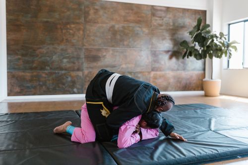 Free Two martial artists practicing grappling techniques indoors on a mat, emphasizing sportsmanship and training. Stock Photo