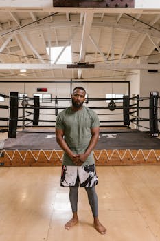 Portrait of a serious athlete in a modern indoor boxing gym, showcasing readiness and strength.