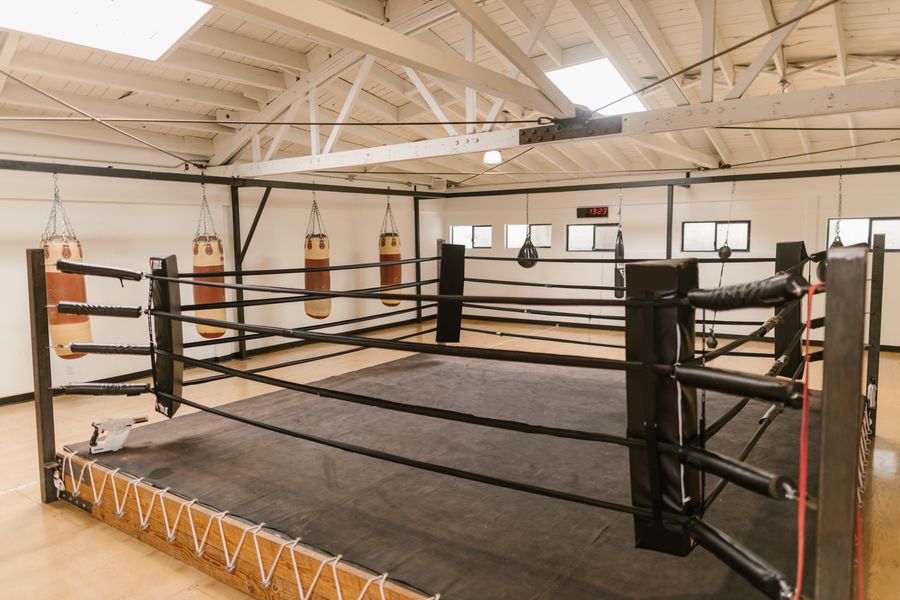 Spacious boxing gym with central ring and heavy bags