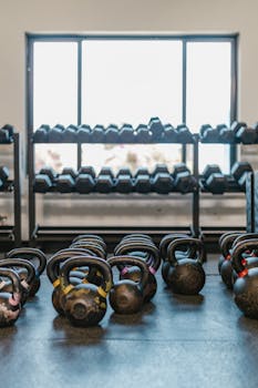 A well-lit gym with kettlebells and dumbbells arranged neatly, ideal for workout inspiration.