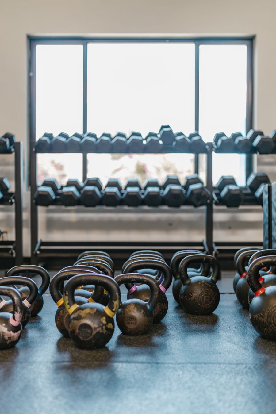Kettlebells and dumbbells arranged neatly on a well-lit gym floor