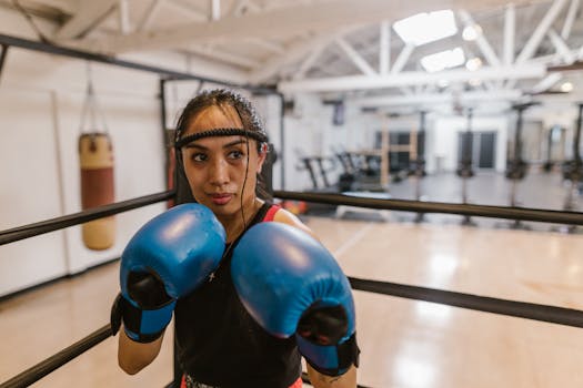 A focused female boxer training with blue gloves in a gym setting.