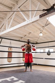 Black male boxer standing confidently in a boxing ring with gloves on.
