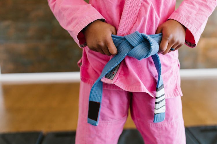 A Close-Up Shot Of A Person Wearing A Pink Gi With A Blue Belt