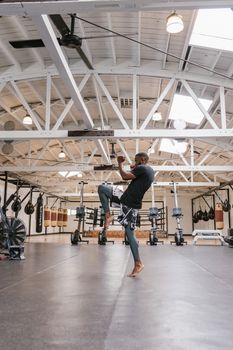 A man practicing martial arts techniques in a well-equipped gym interior.