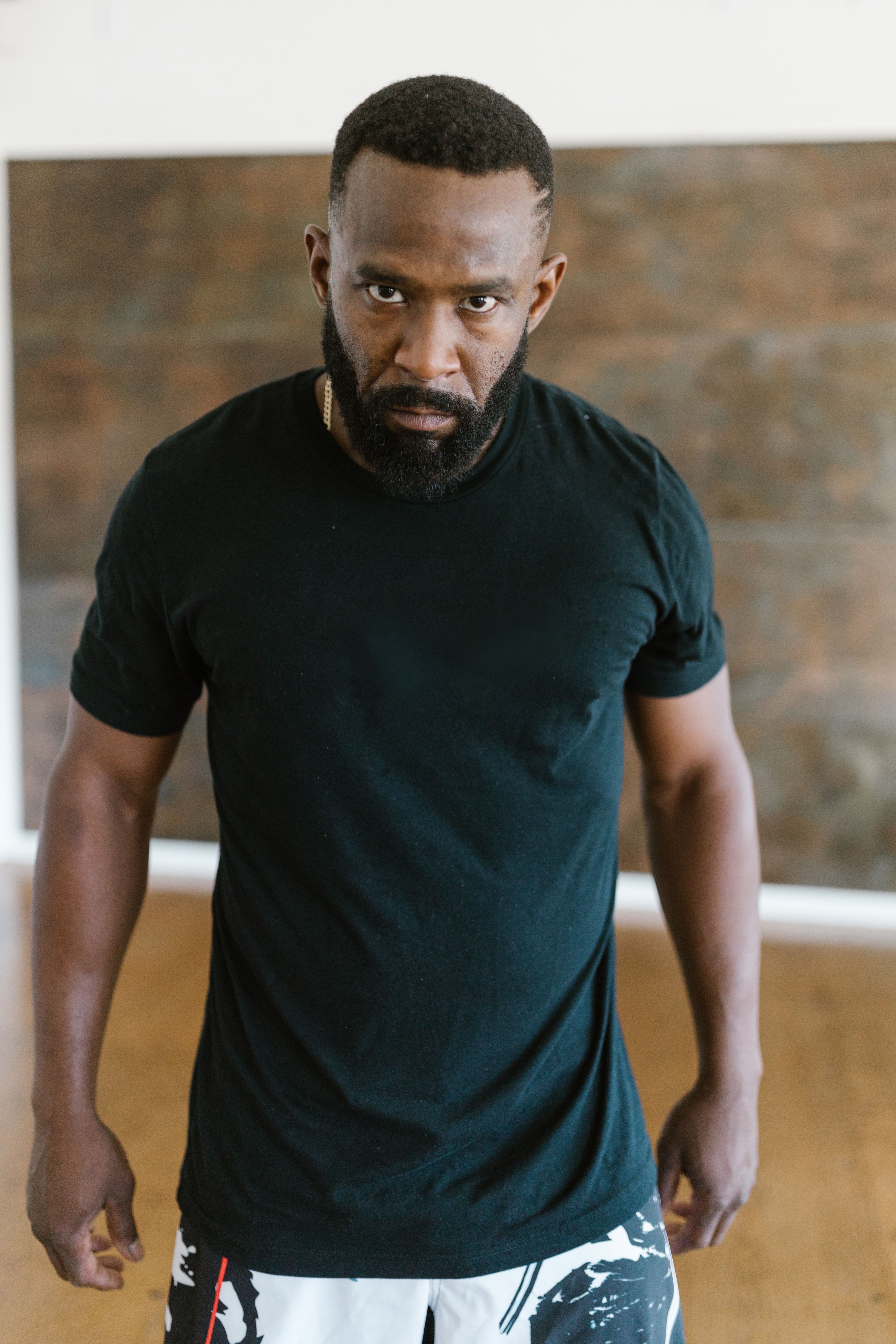 Portrait of a muscular man with a strong expression, wearing a black t-shirt indoors.