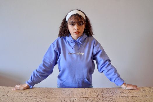 A Curly-Haired Woman in Blue Hoodie Posing while Looking at Camera