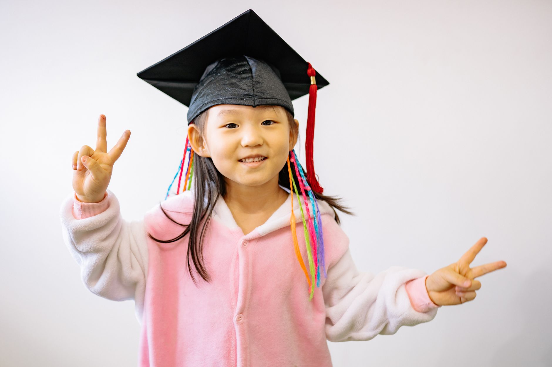 international school graduation party Egypt — A cheerful child in a graduation cap expressing happiness and success while mak