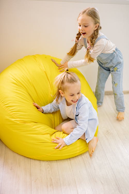 Free Two Pretty Girls Playing With Yellow Bean Bags Stock Photo