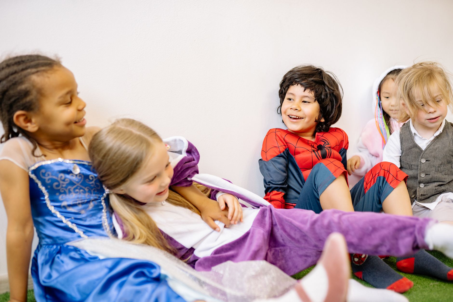 Nile University event planner — Group of diverse children joyfully playing in colorful costumes indoors.
