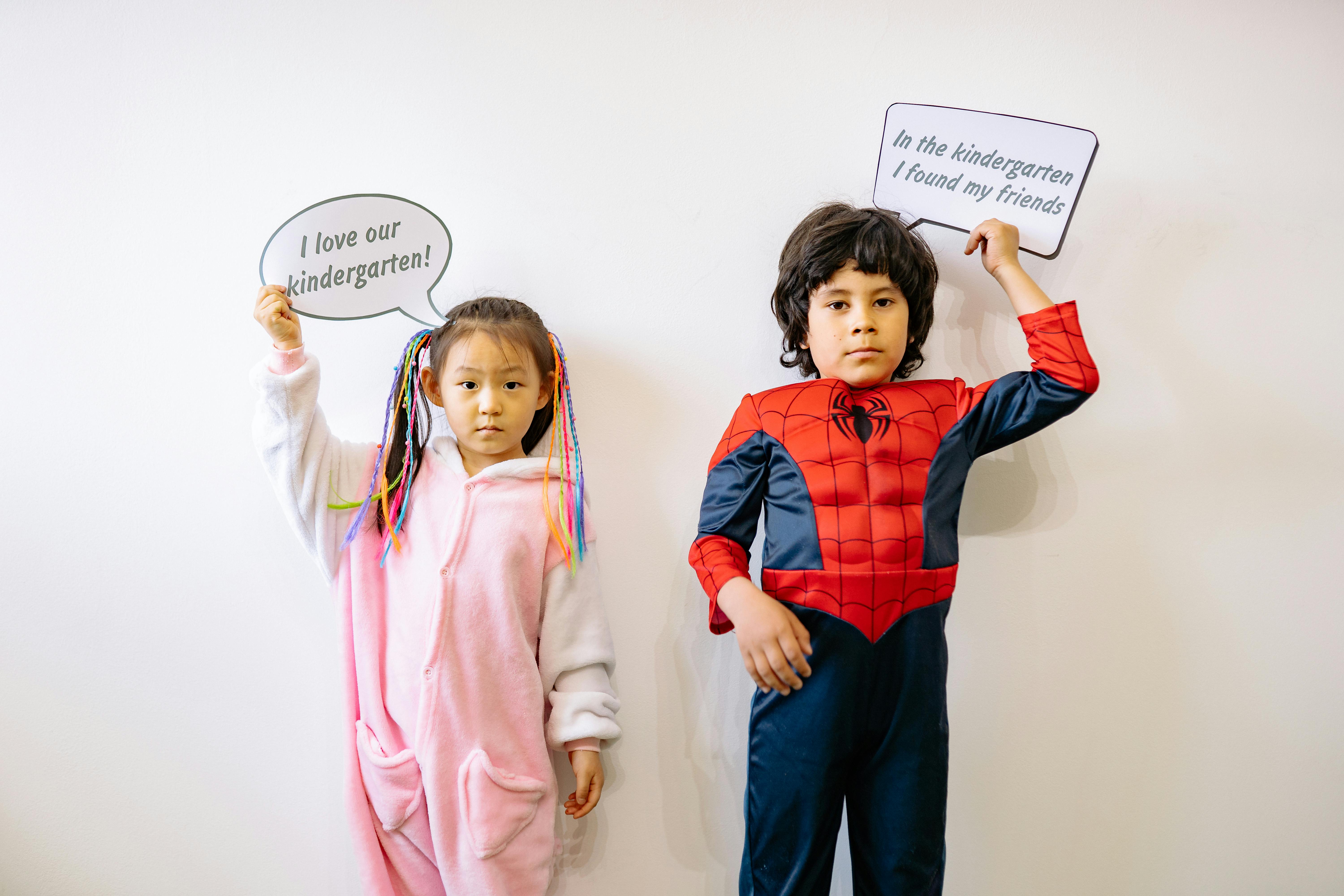 a boy and a girl wearing costumes holding cardboards with text