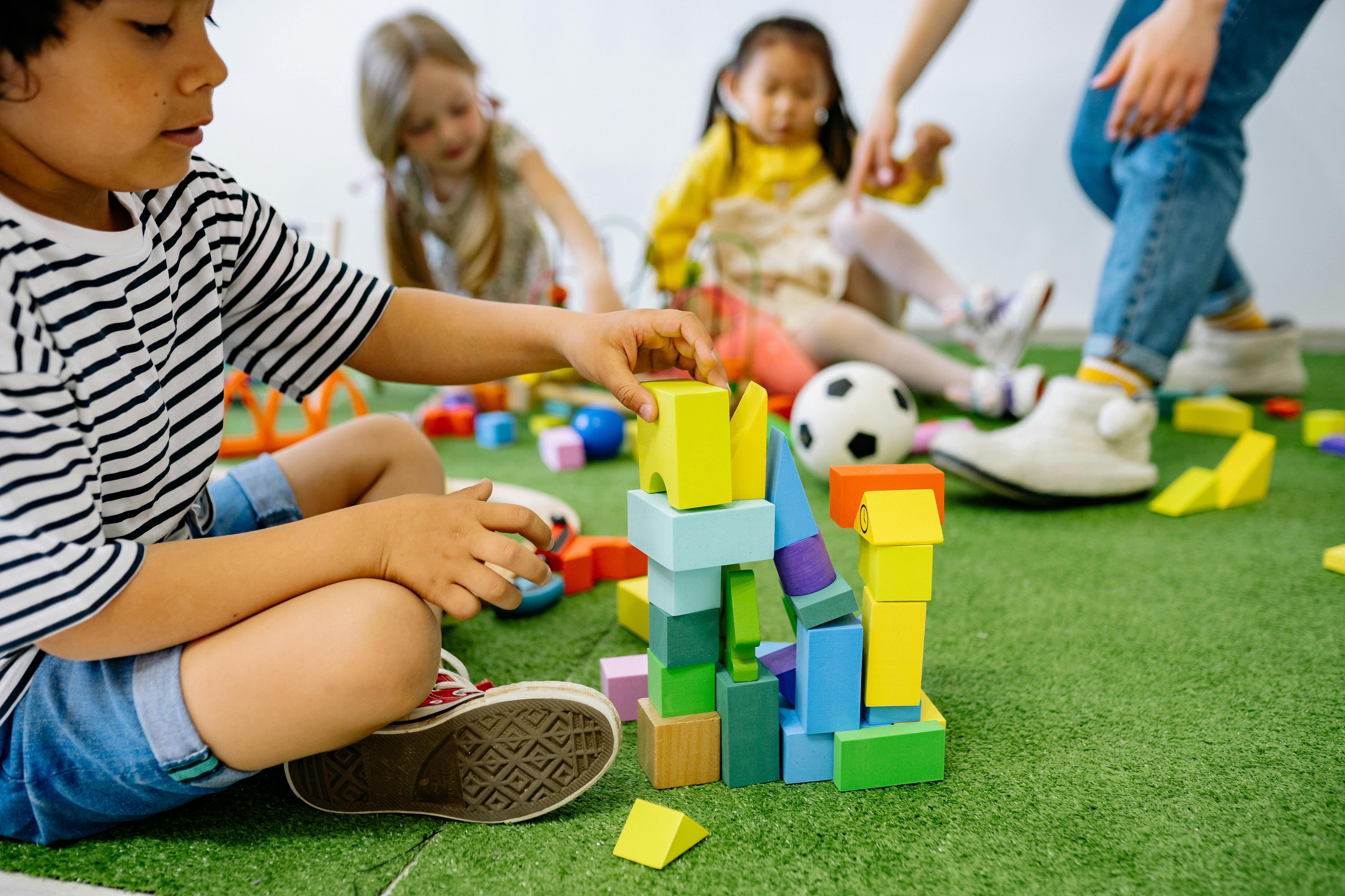 boy in white and black striped shirt playing wooden blocks