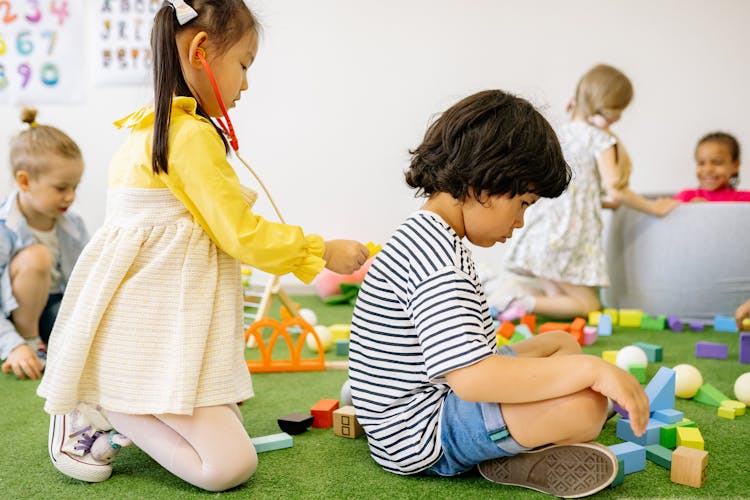 Girl In Yellow Dress Playing Doctor With A Boy In Striped Shirt