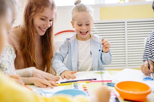 Free Happy children and teacher enjoying a creative arts and crafts session in a cheerful classroom setting. Stock Photo