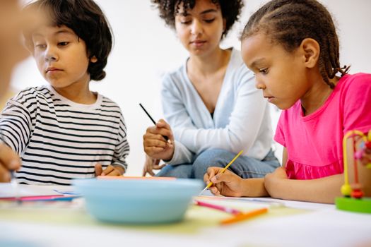 Children painting and learning with a teacher in a creative classroom setting.