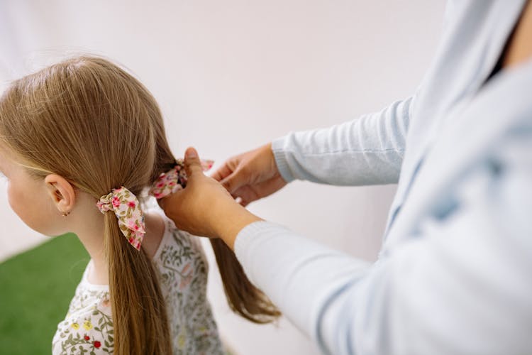 Woman Fixing The Hair Of A Blonde Girl