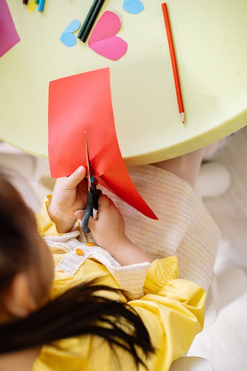 Girl in Yellow Dress Cutting A Red Art Paper