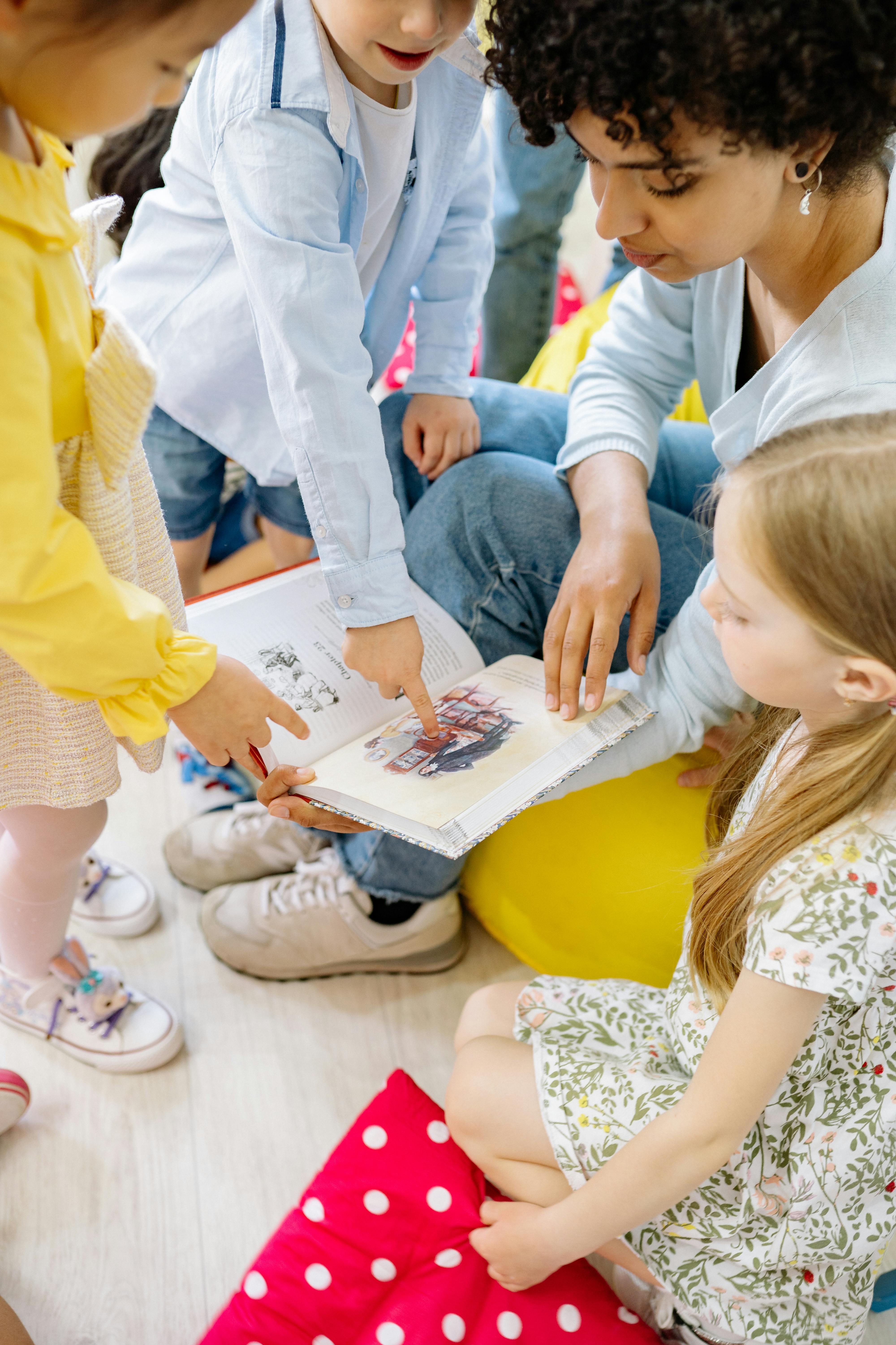 children looking at a book holding by a teacher