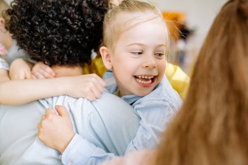 Blonde Girl in Blue Long Sleeve Shirt Smiling and Hugging A Person