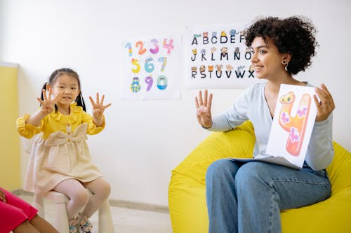 Free Girl in Yellow Long Sleeve Dress Learning To Count With Her Teacher Stock Photo