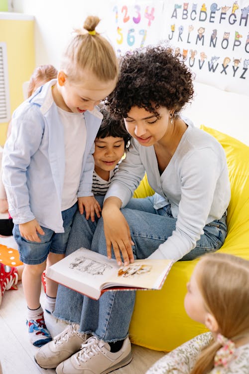 Free School Teacher Showing A Book To The Children Stock Photo