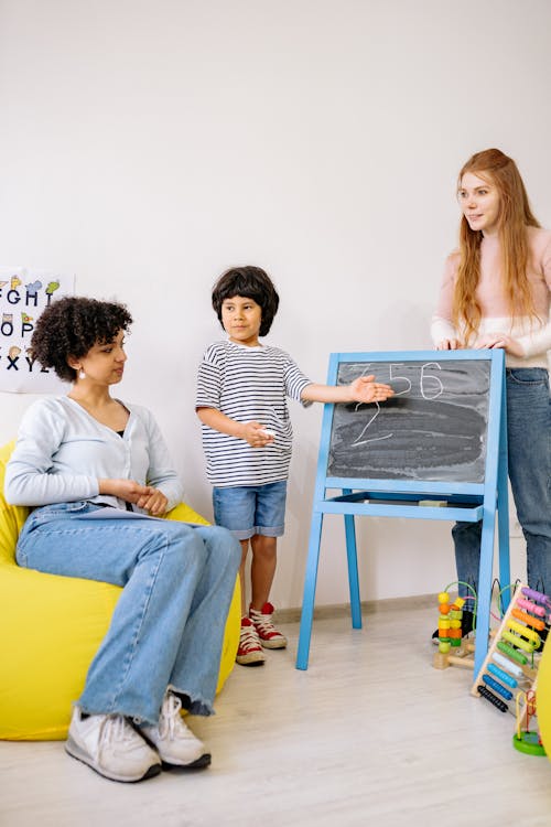 Free A Boy Standing Beside A Blackboard With His Teachers Stock Photo