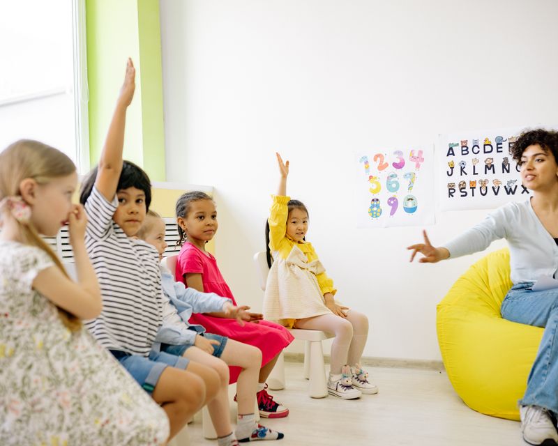 Teacher giving a lesson as students raise their hands