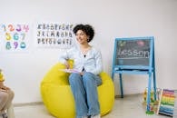 Preschool Teacher Sitting on Yellow Bean Bag Inside The Classroom