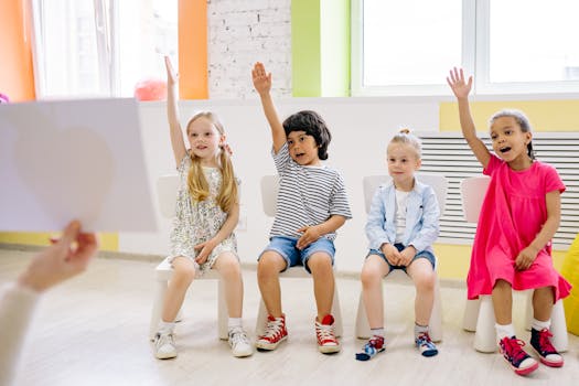 Four children eagerly raising their hands in a vibrant and colorful classroom setting.