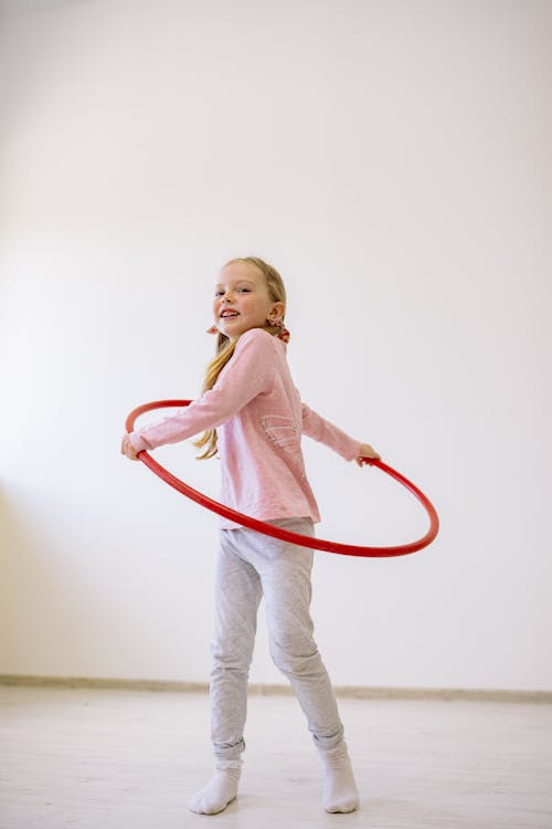 Free Girl in Pink Long Sleeve Shirt and White Pants Playing With A Hula Hoop Stock Photo