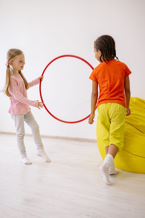 Two Girls Learning To Use A Hula Hoop