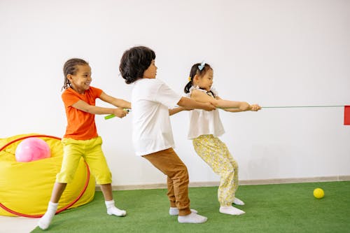 Children Playing Tug Of War On Green Carpet