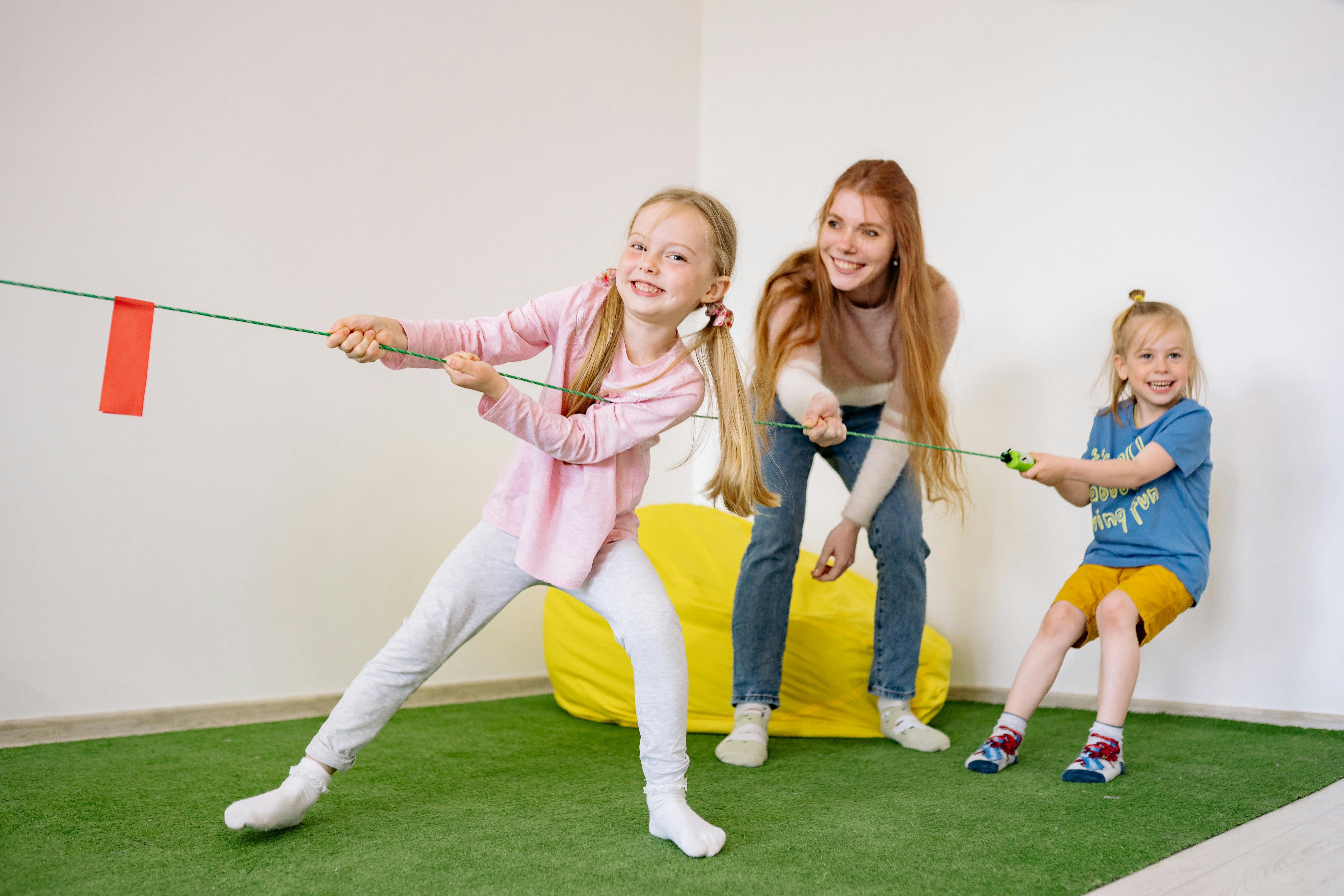 two girls and a woman pulling a rope together