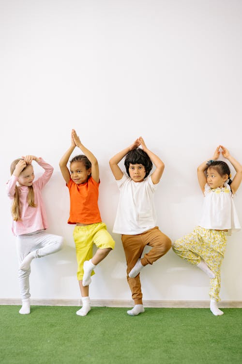 Children Balancing On One Foot With Hands Raised